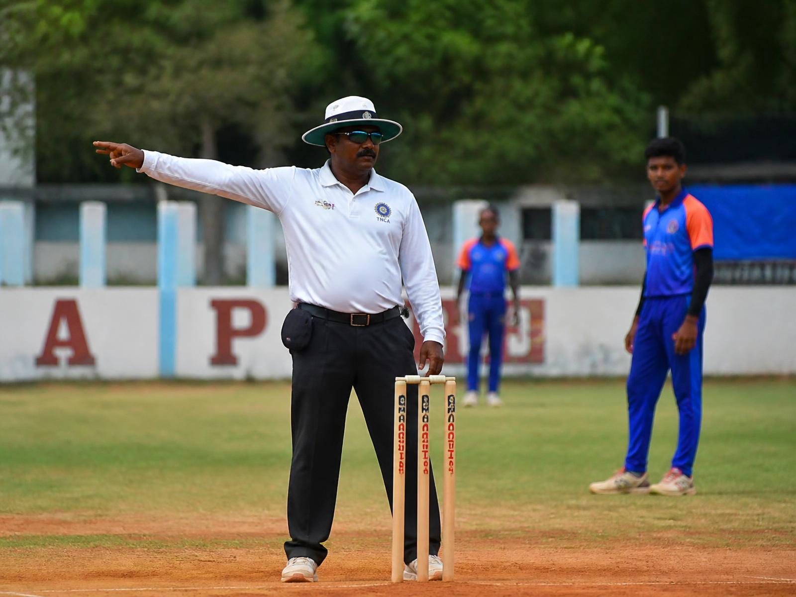 Qualified umpire signalling with a live scoring setup at a cricket match in Chennai